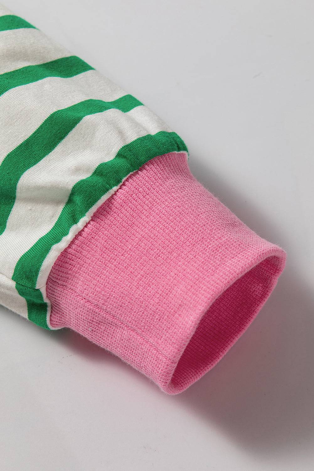 a pink and green striped shirt laying on a white surface