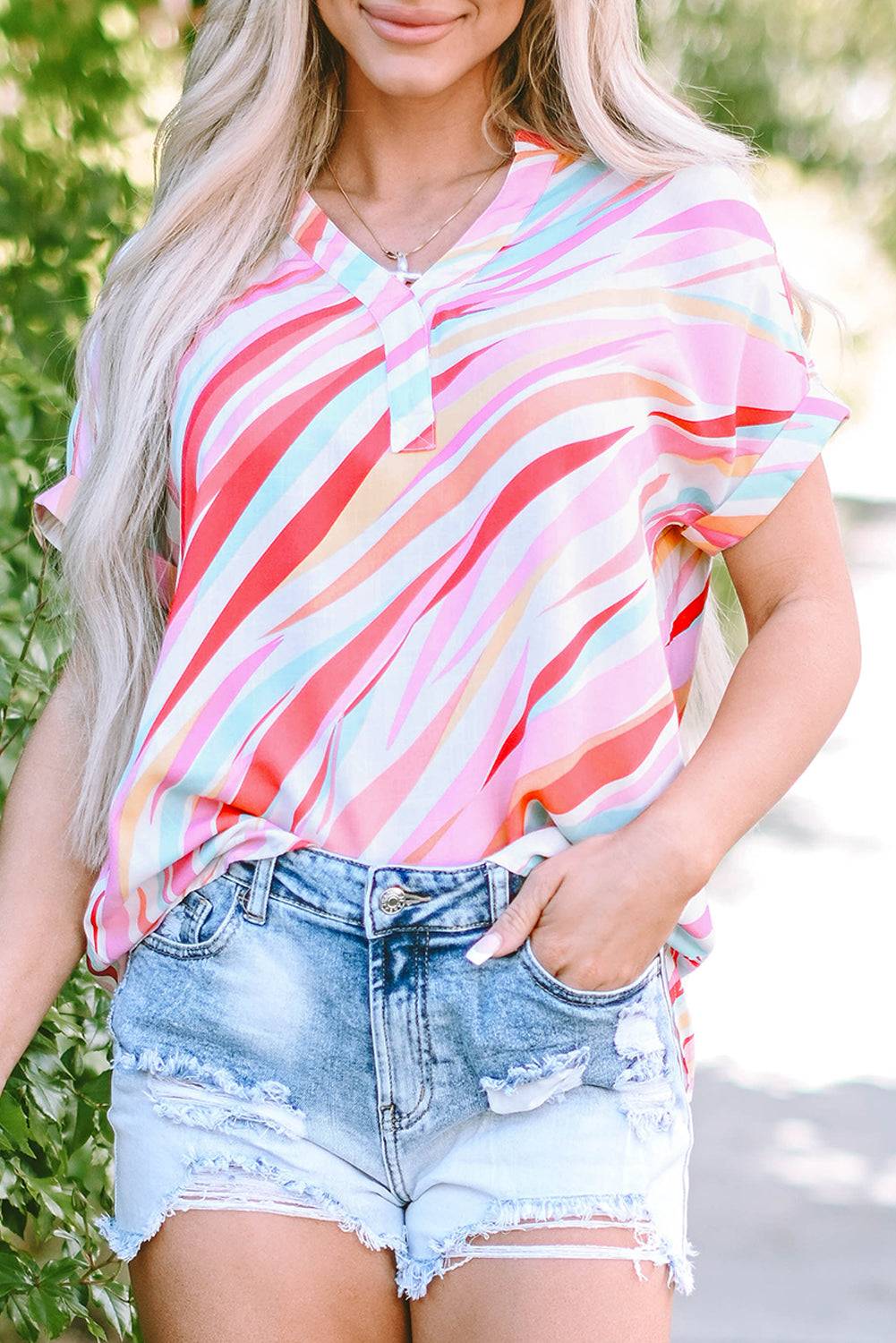 a woman wearing a colorful striped top and denim shorts