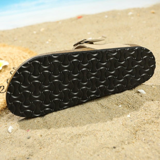 a pair of black shoes sitting on top of a sandy beach