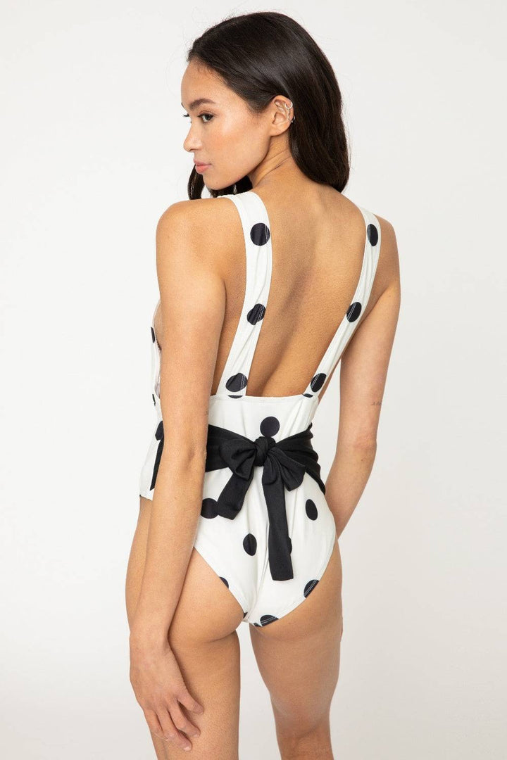 a woman wearing a white and black polka dot swimsuit
