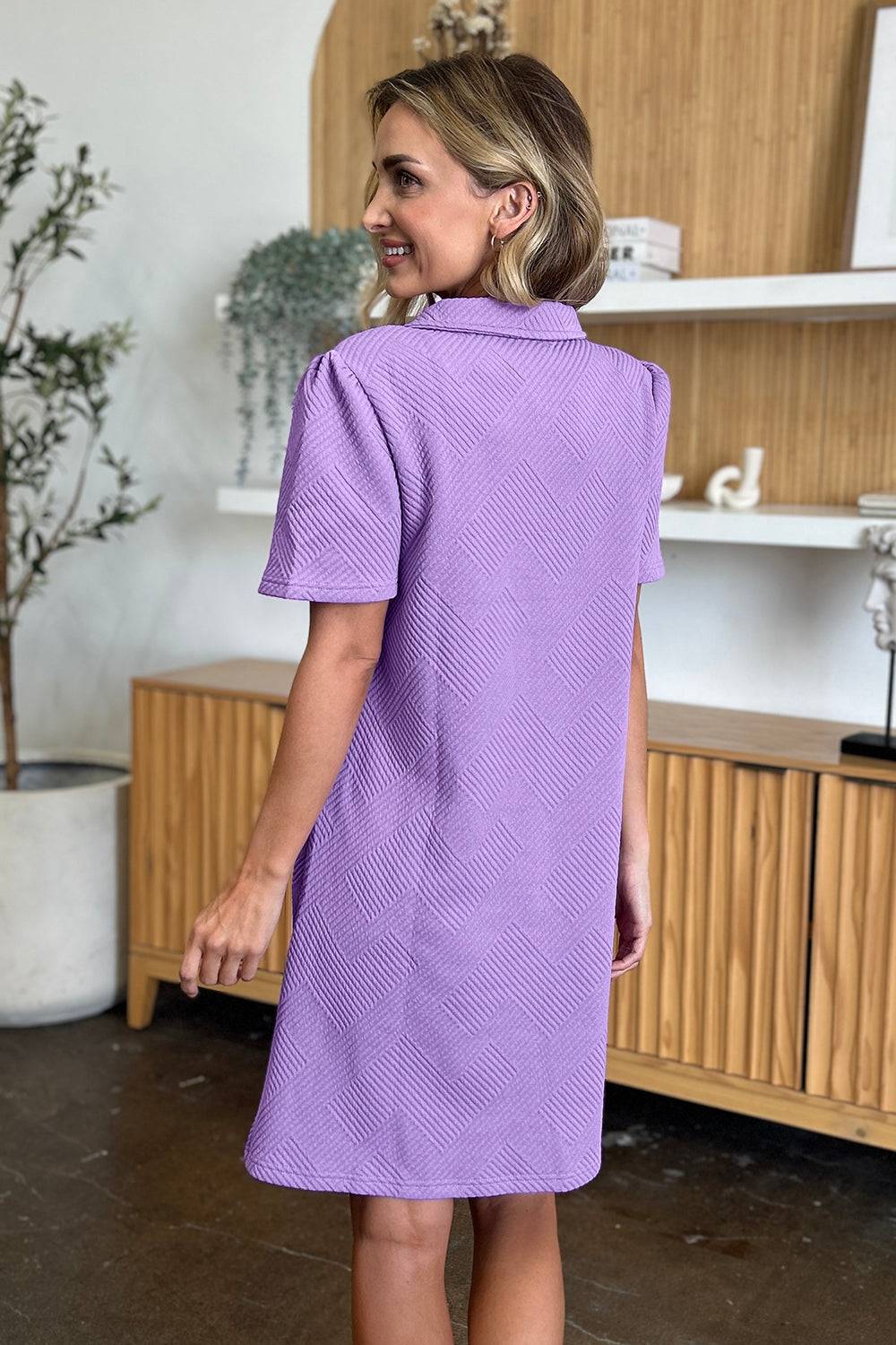 a woman in a purple dress standing in a room