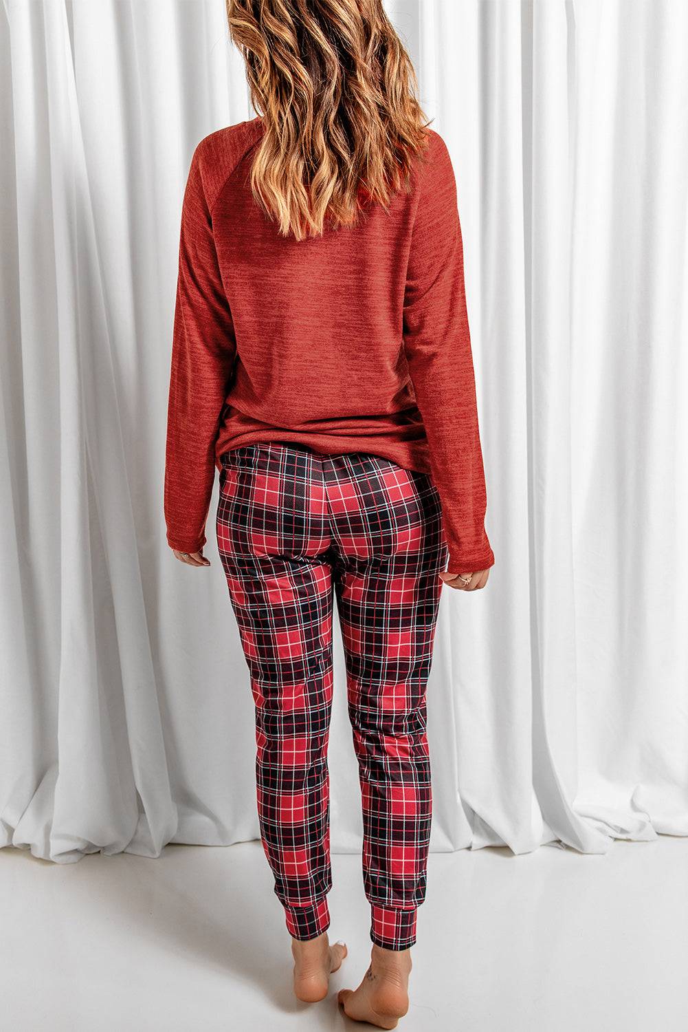 a woman wearing a red sweater and plaid pants