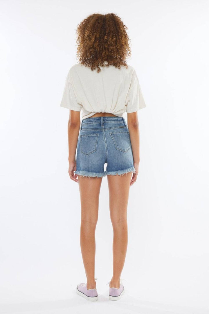 a woman wearing a white t - shirt and denim shorts