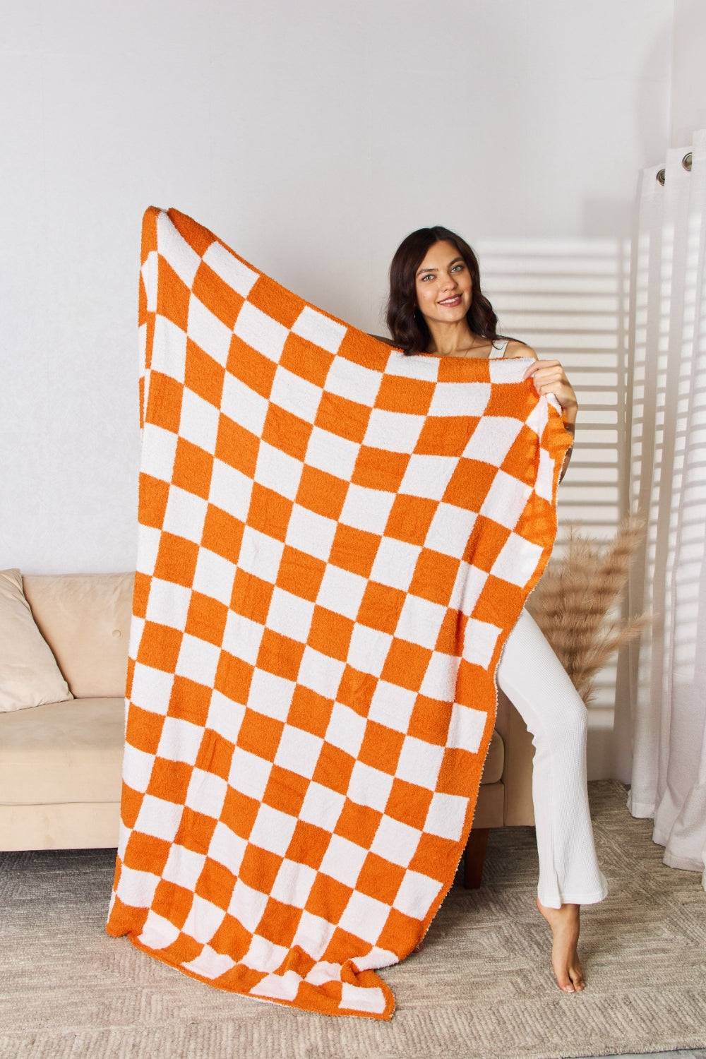 a woman holding a large orange and white checkered blanket