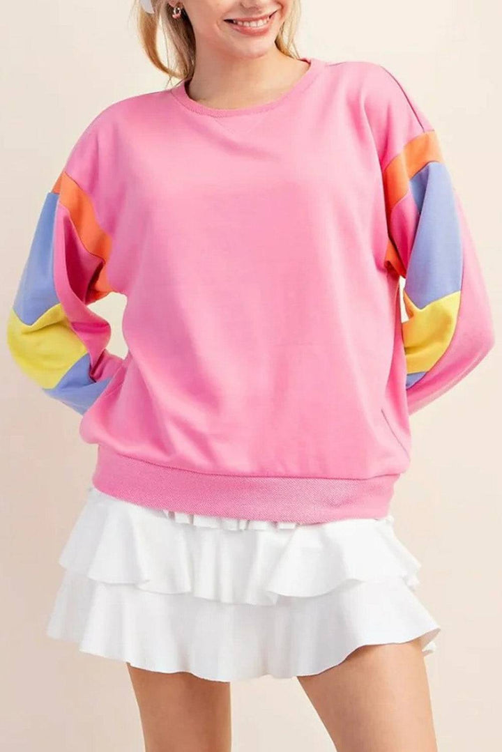 a woman wearing a pink sweater and white skirt