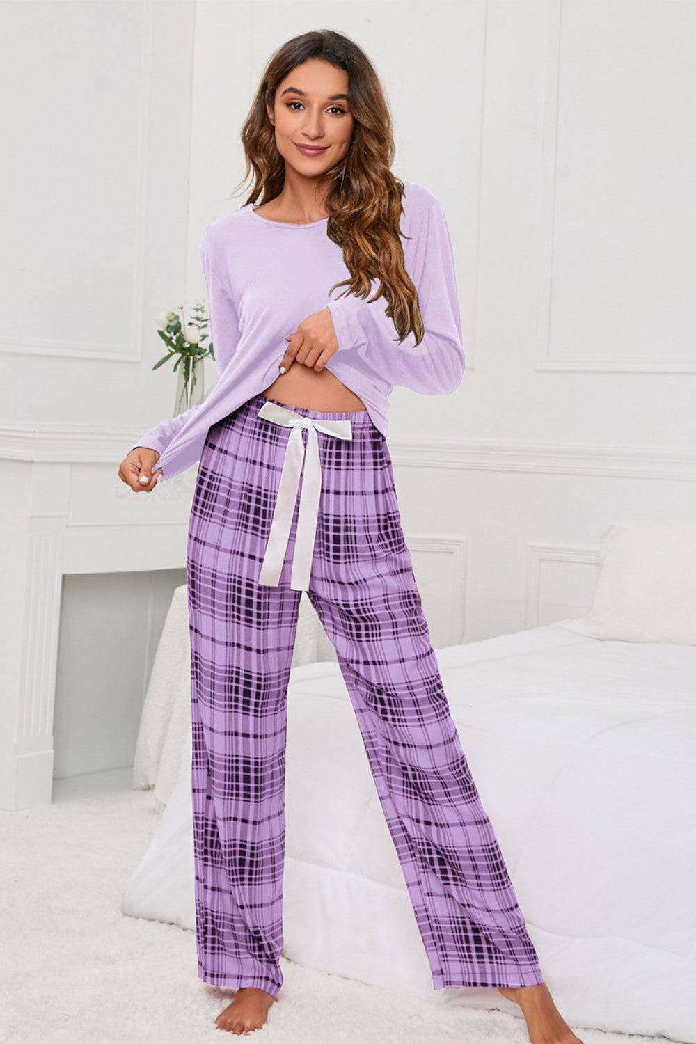 a woman wearing a purple top and plaid pants