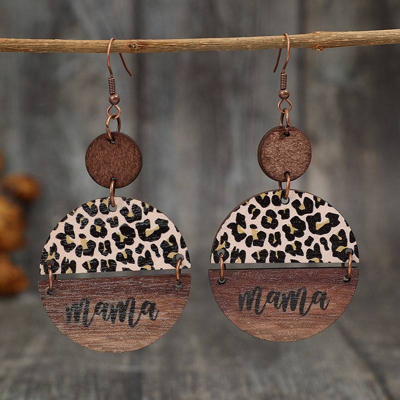 a pair of leopard print earrings hanging from a wooden hook