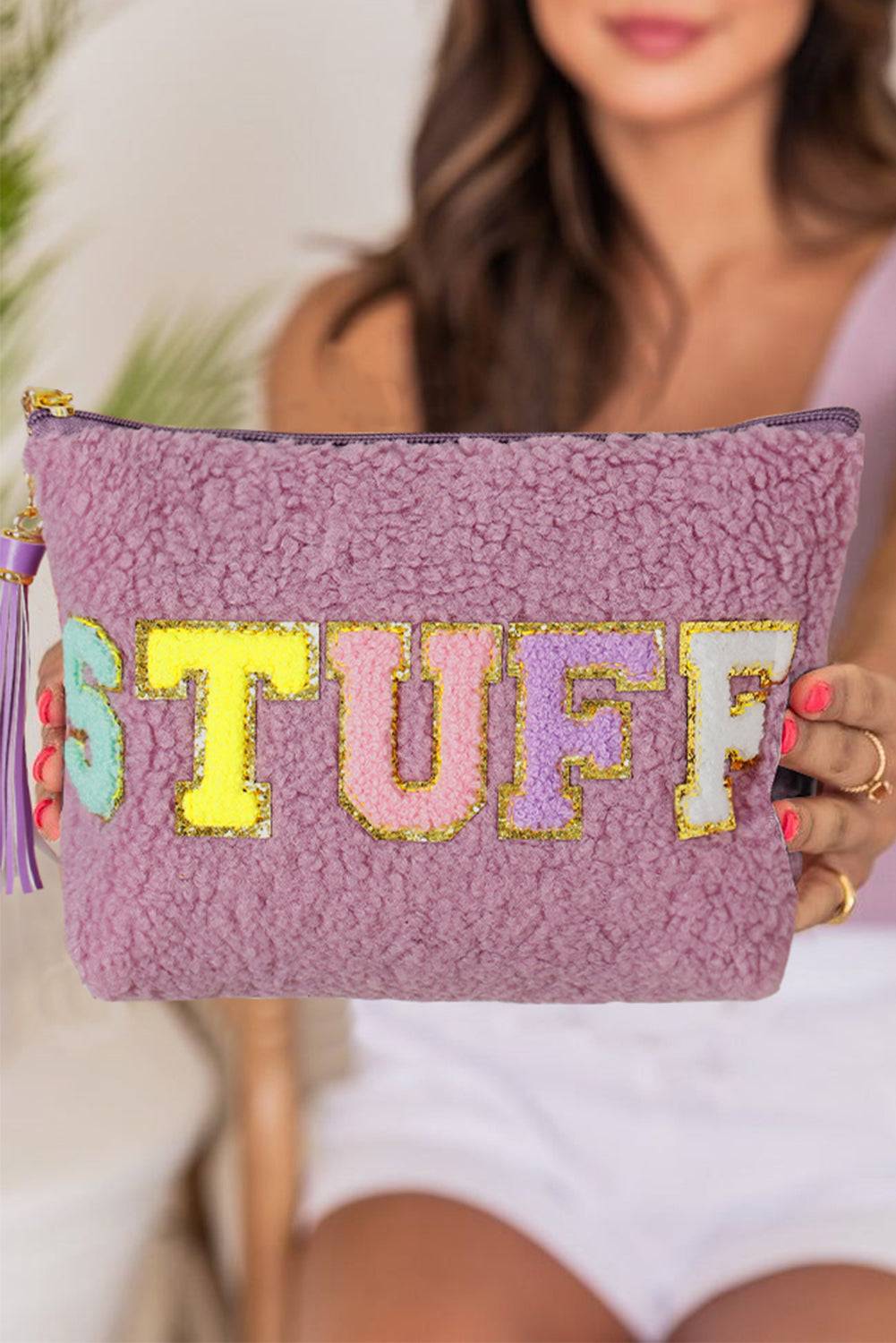a woman holding a purple purse with the word stuff on it