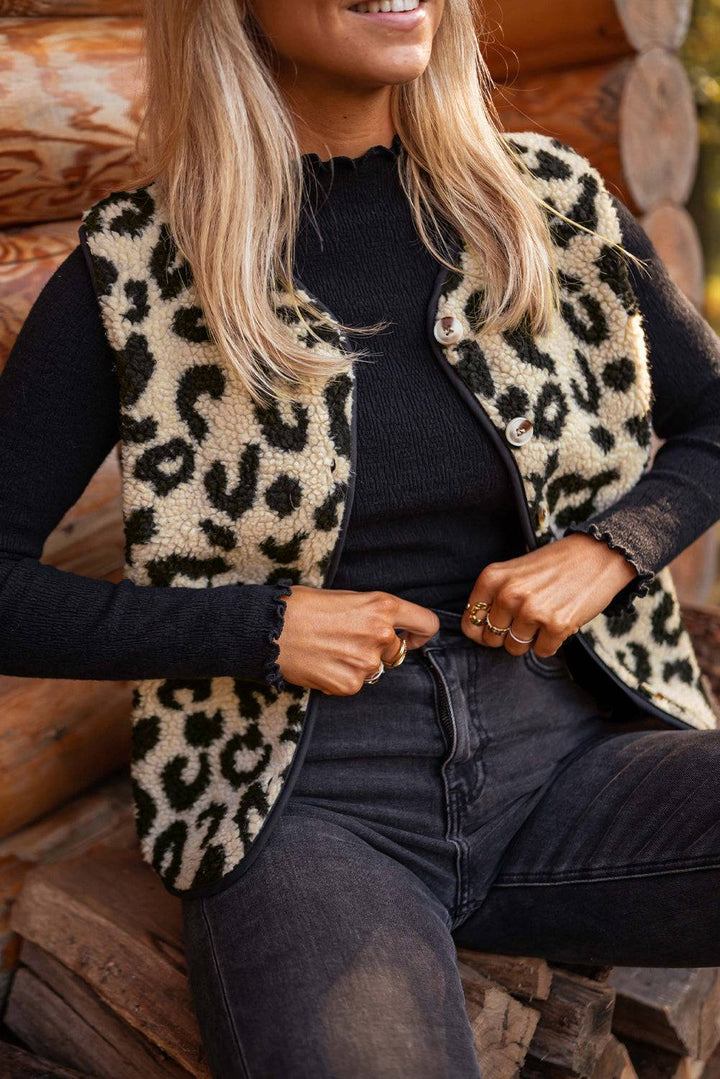 a woman sitting on a log wearing a leopard print vest