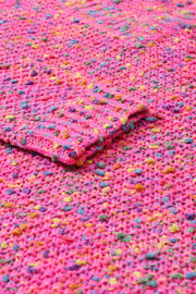 a pink crocheted blanket laying on top of a table