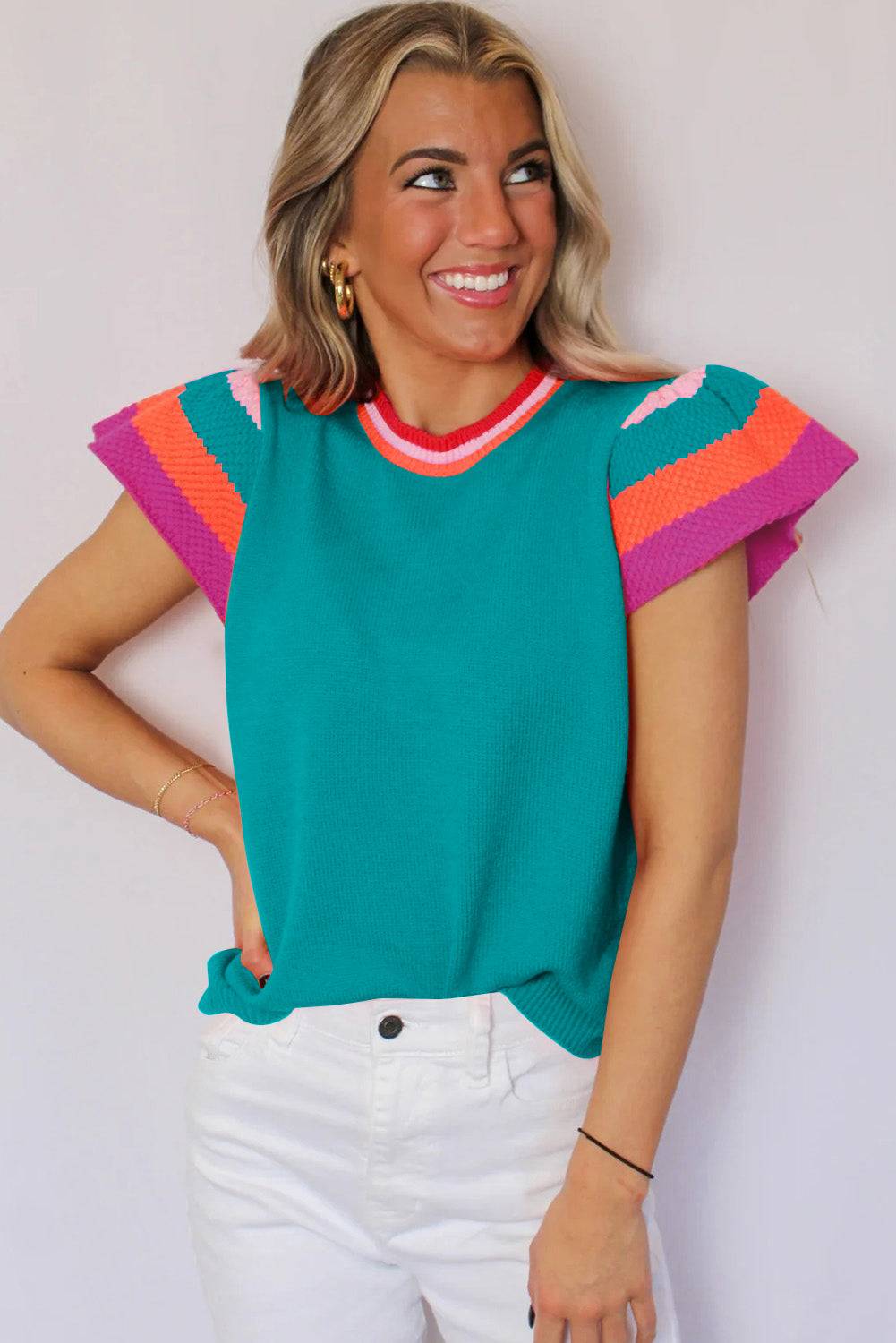 a woman wearing a green sweater and white pants