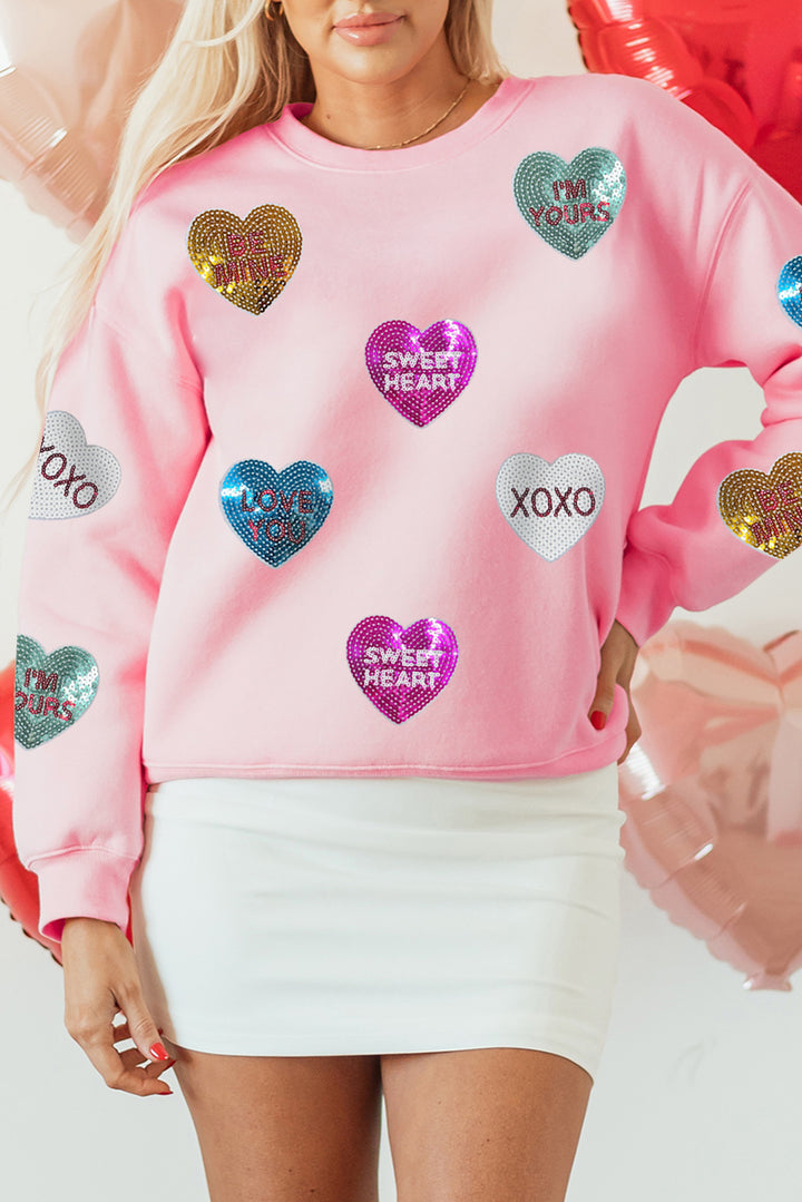 Close-up of Pink Sequin Romantic Letters Heart Graphic Valentines Sweatshirt at Faith & Co. Boutique, highlighting glittery heart graphics with phrases like 'XOXO' and 'Sweet Heart'.