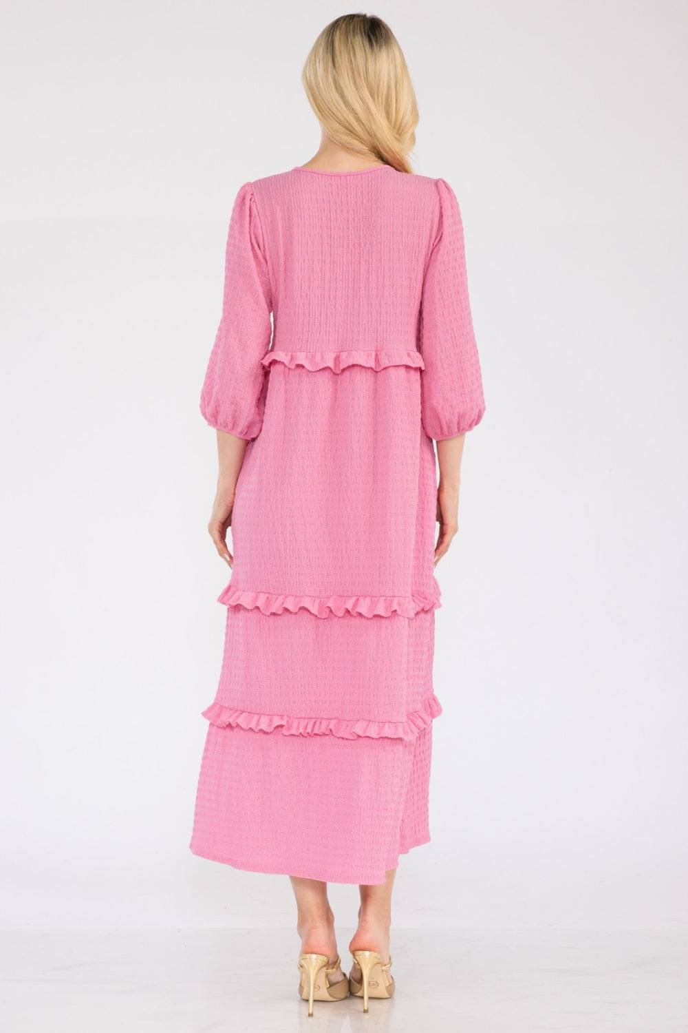 a woman wearing a pink dress with ruffles