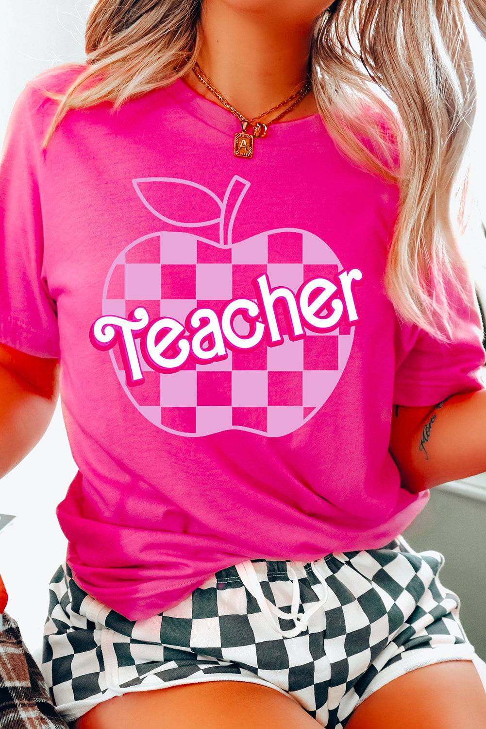 a woman wearing a pink teacher shirt and checkered shorts