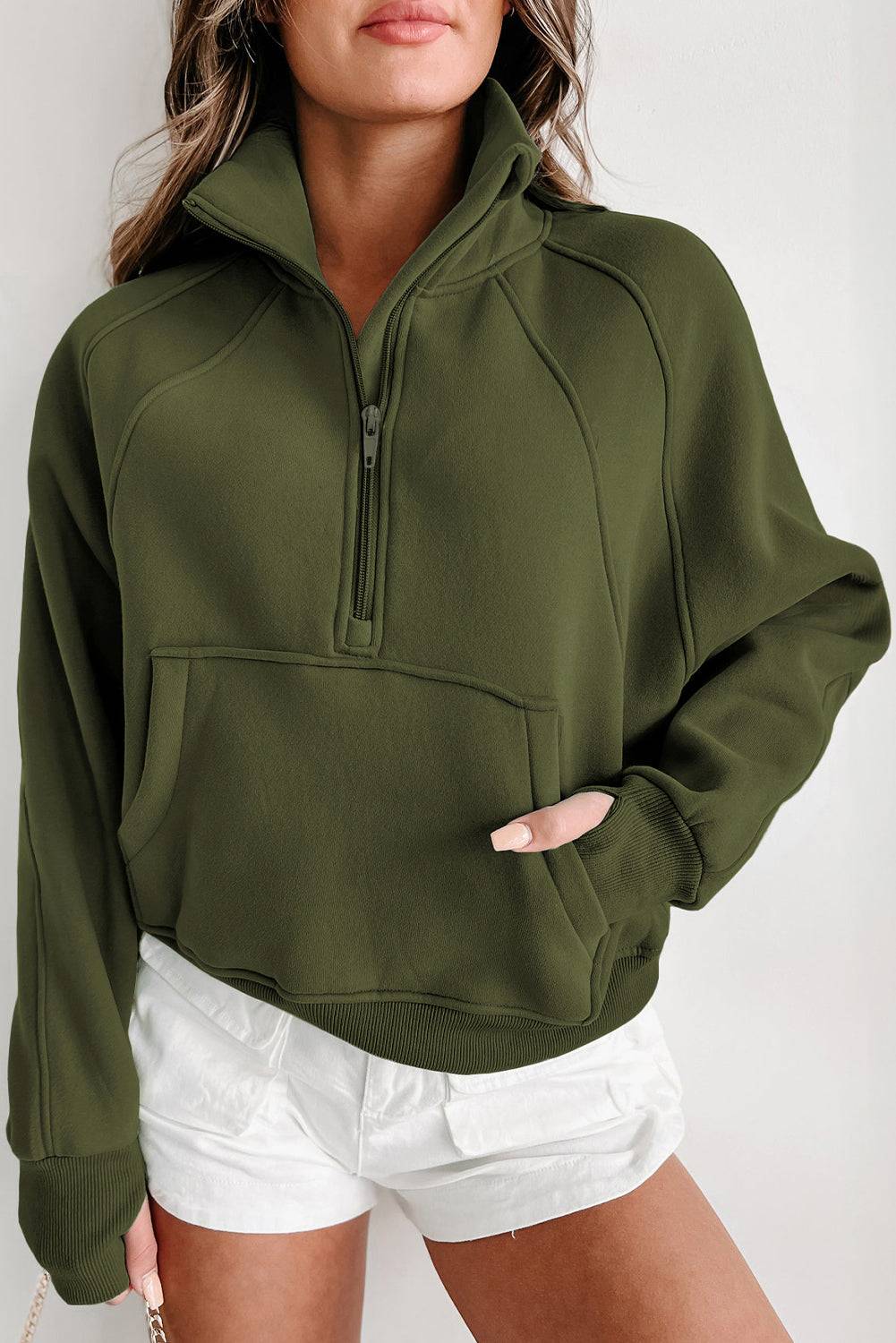 a woman wearing a green sweatshirt and white shorts