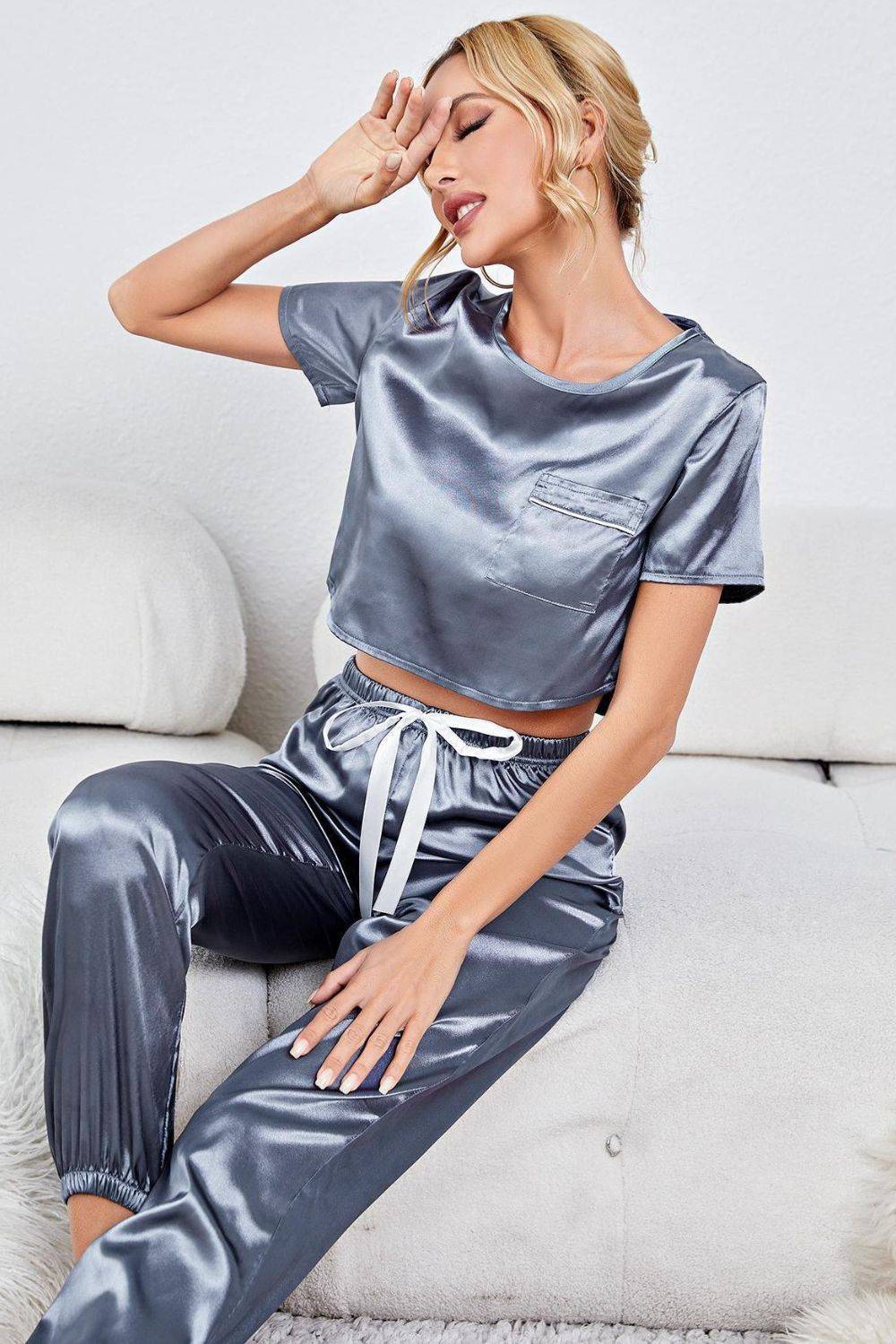 a woman sitting on a couch wearing a silver top and pants