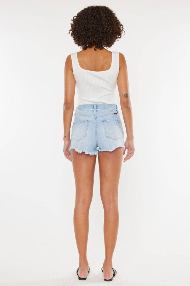 a woman in a white tank top and denim shorts