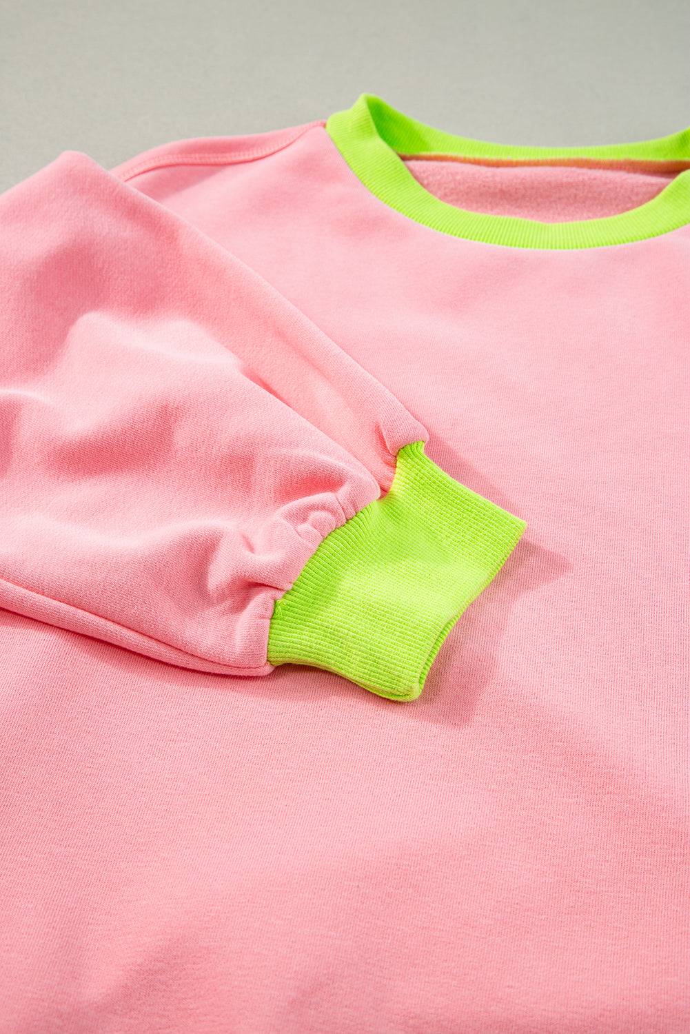 a pink shirt with a green patch on it