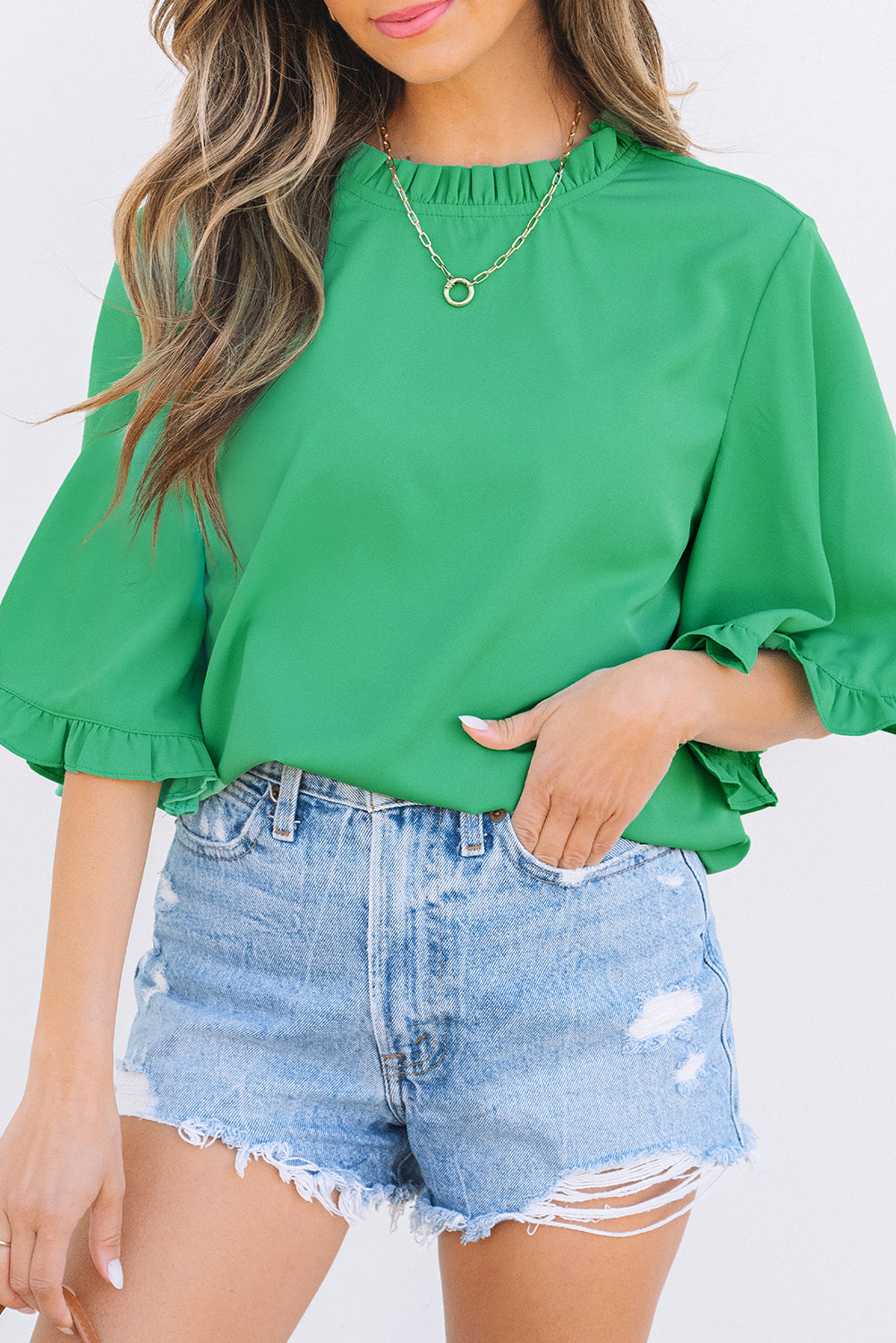 Close-up of Green Frilly Round Neck Wide Half Sleeve Blouse tucked into denim shorts, highlighting ruffle sleeve detail.