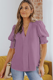 a woman wearing a purple blouse and jeans