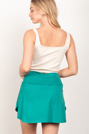 a woman in a white top and a green skirt