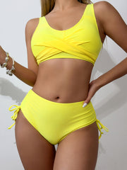a woman in a yellow bikini top holding a cell phone