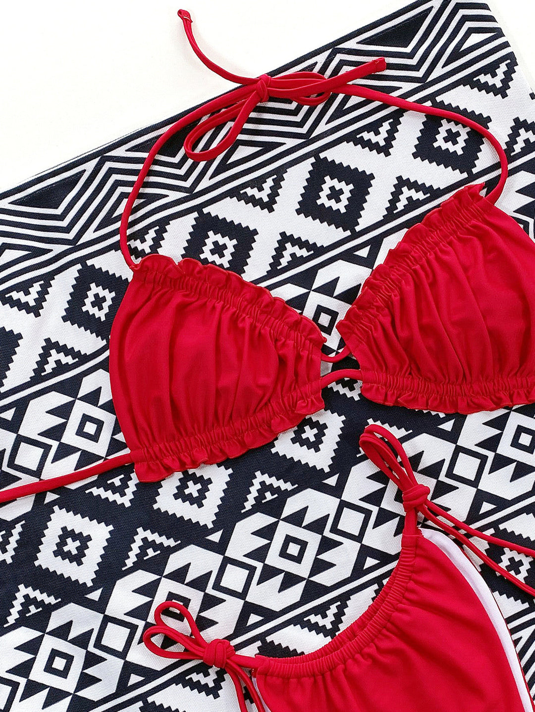 two red bikinisuits laying on a black and white pattern