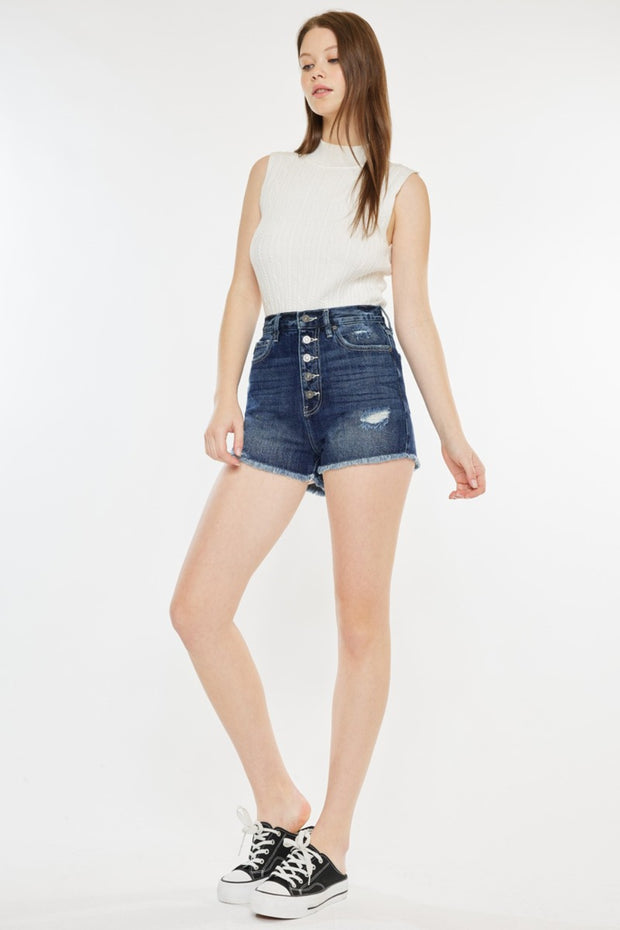 a woman in a white top and denim shorts