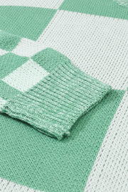 a green and white blanket laying on top of a bed