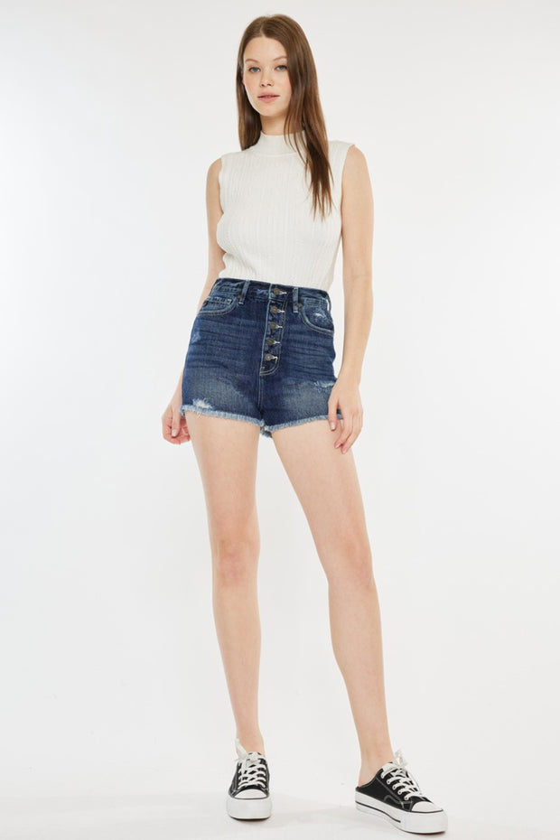 a woman wearing a white top and denim shorts
