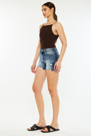 a woman in a black tank top and denim shorts