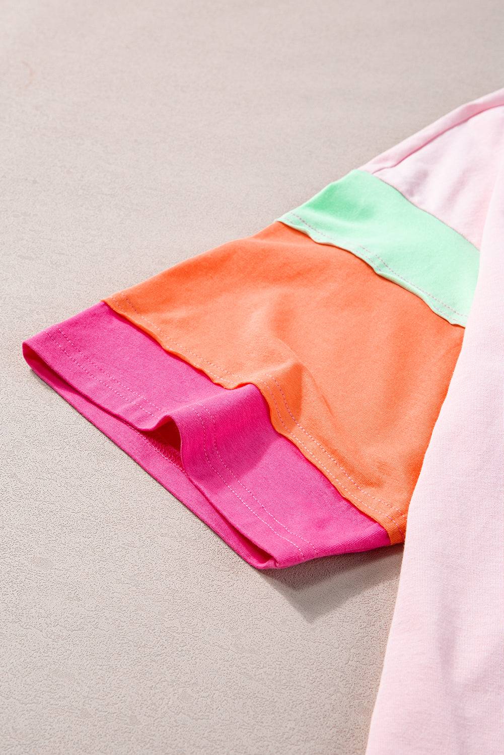 a pink, orange, and green shirt laying on the ground