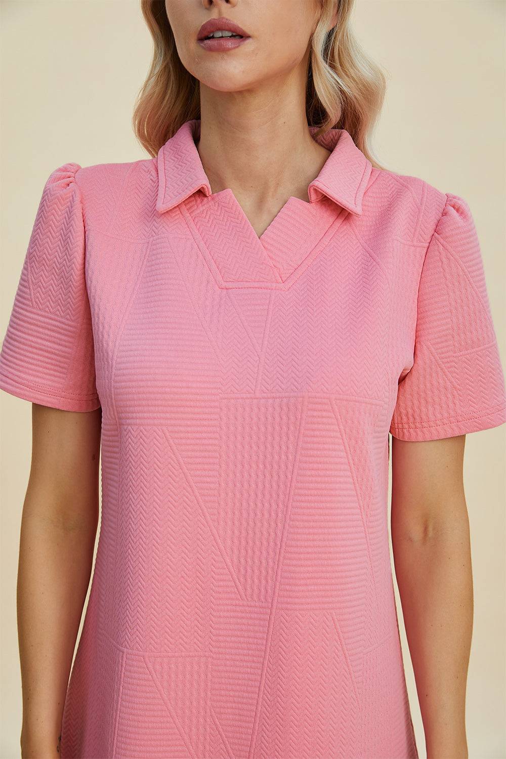a woman wearing a pink shirt with a collar