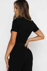 a woman in a black jumpsuit with her back to the camera