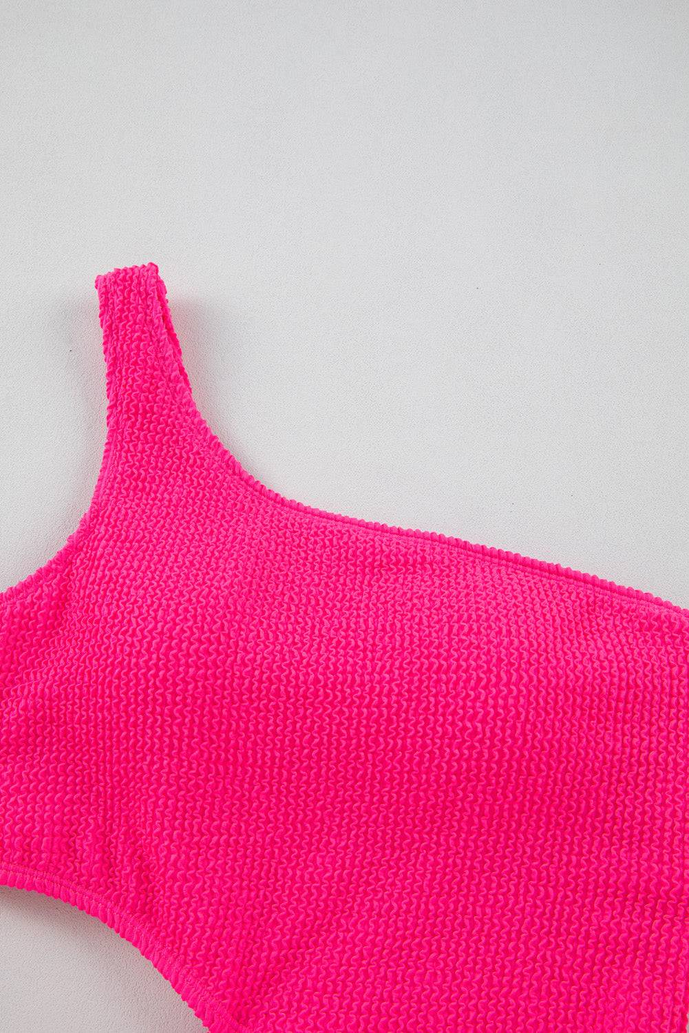 a pink knitted sweater laying on top of a white surface