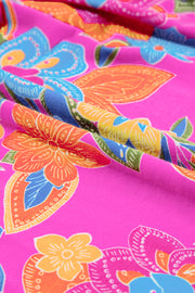 a close up of a pink fabric with colorful flowers on it