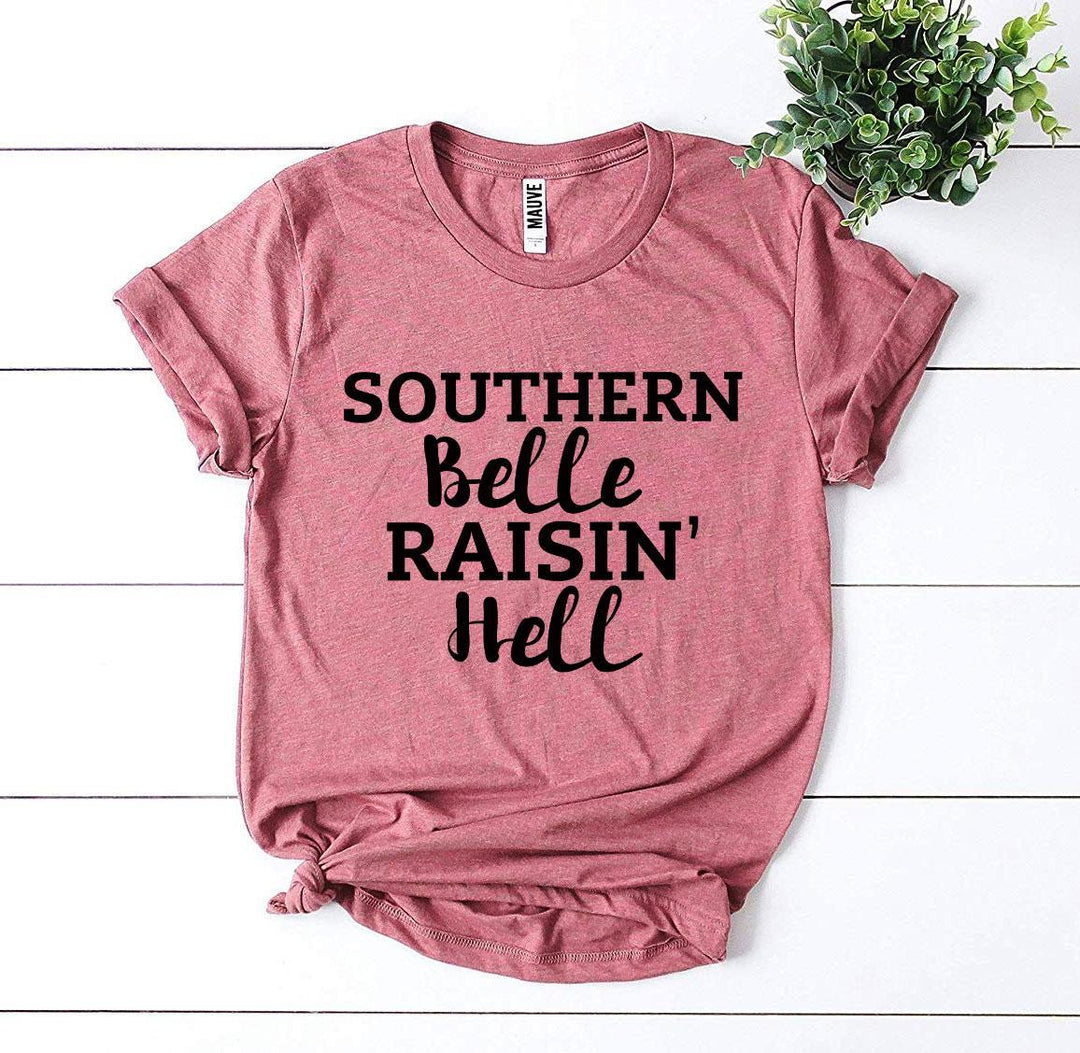 a pink shirt that says southern belle raiin'hell