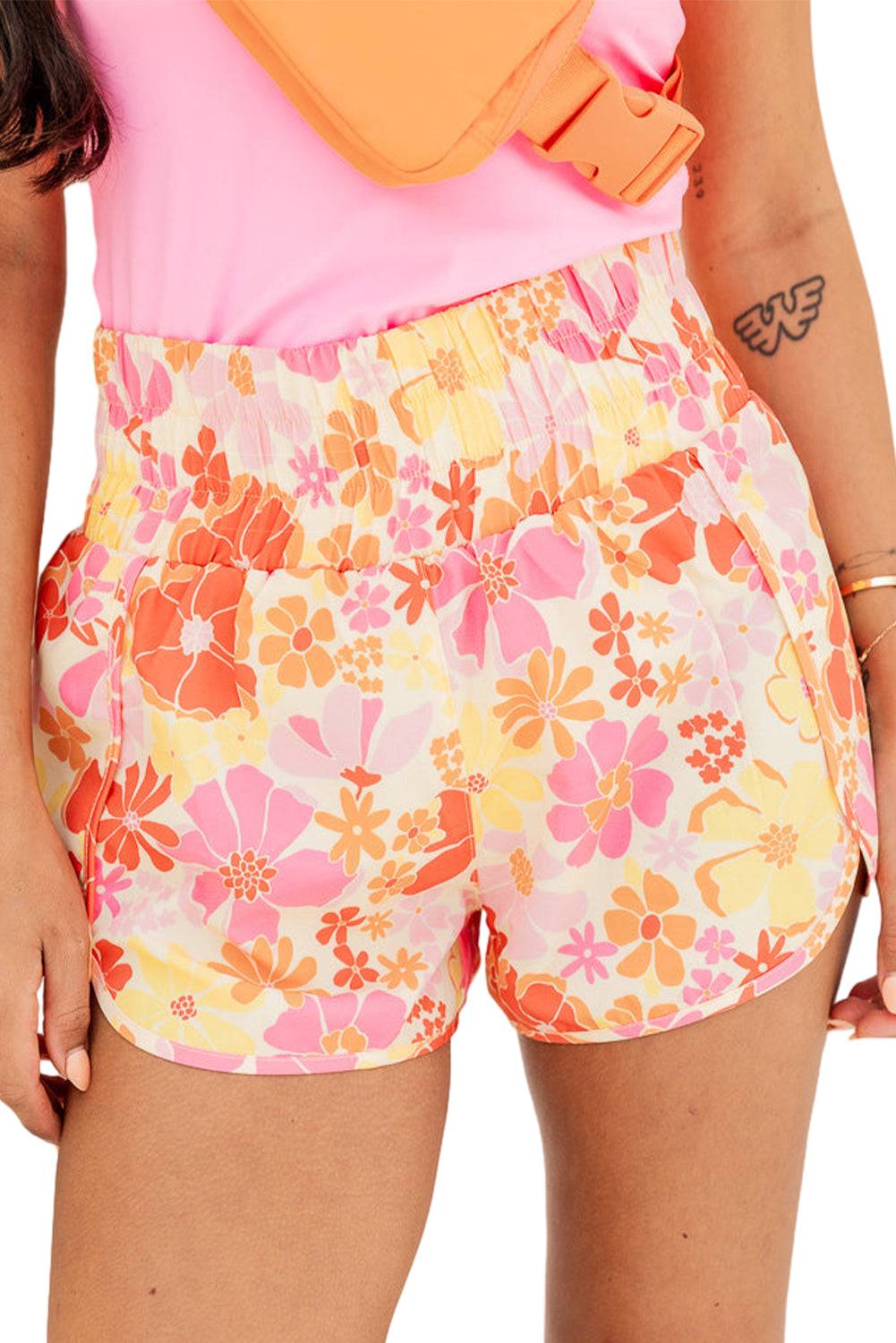 a woman wearing a pink top and floral shorts