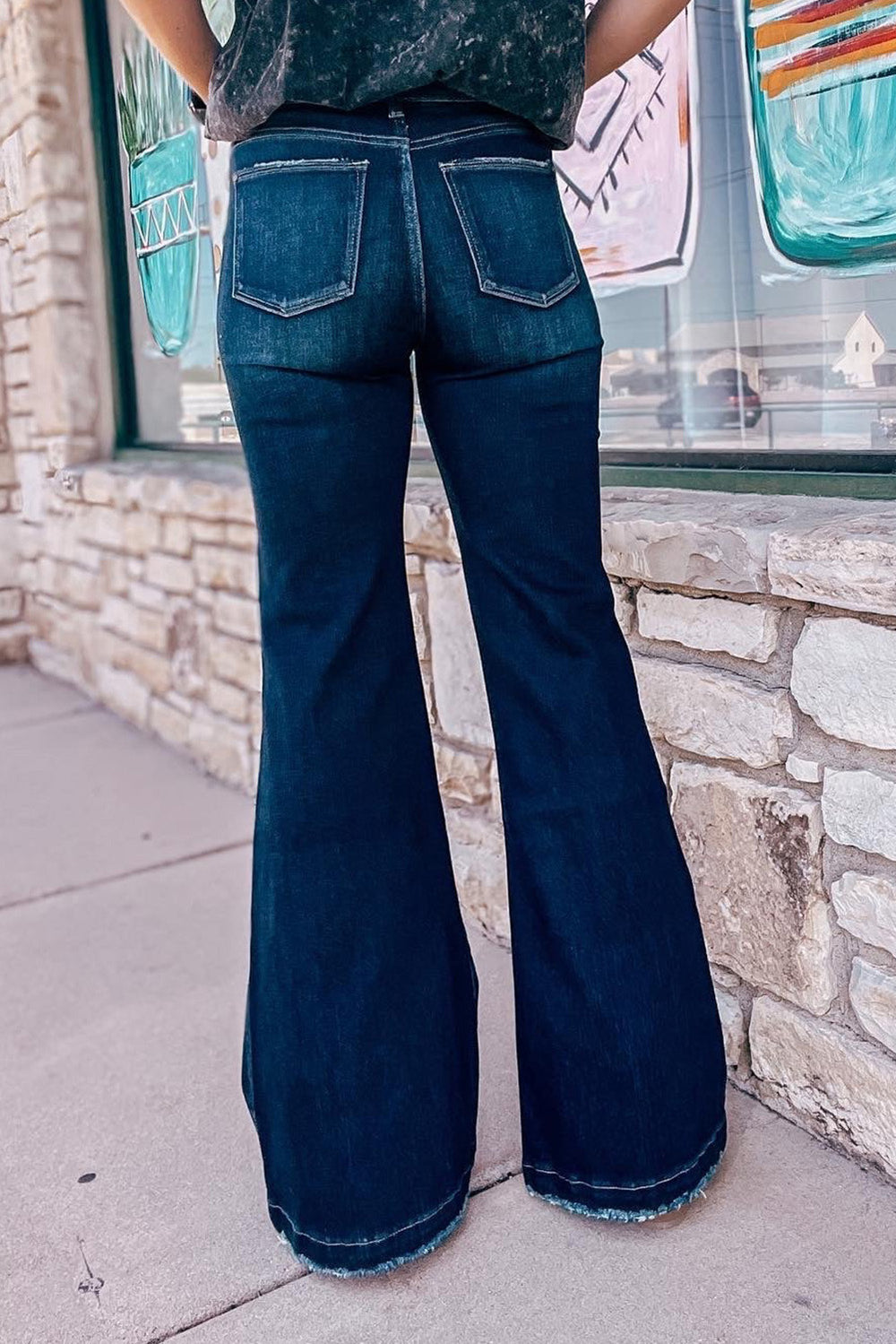 a woman standing in front of a store window with her back to the camera