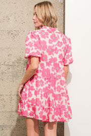 a woman standing in front of a wall wearing a pink dress