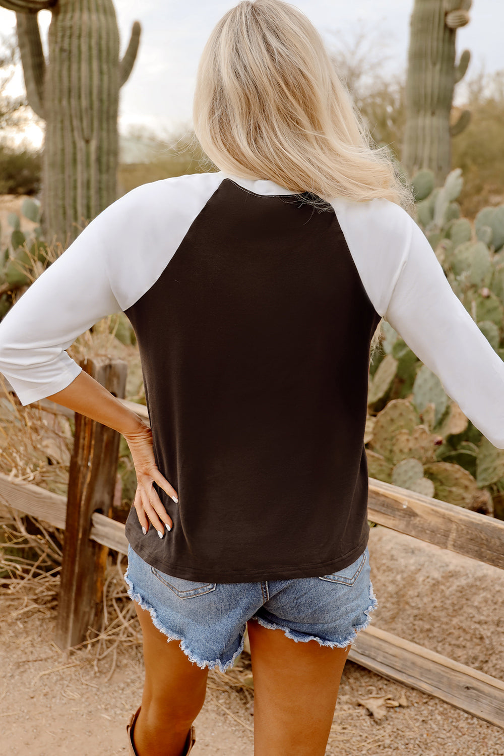 back view of model in Brown Western Yeehaw Graphic Vintage Raglan Long Sleeve Top paired with distressed shorts
