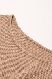 a close up of a tan sweater on a white background