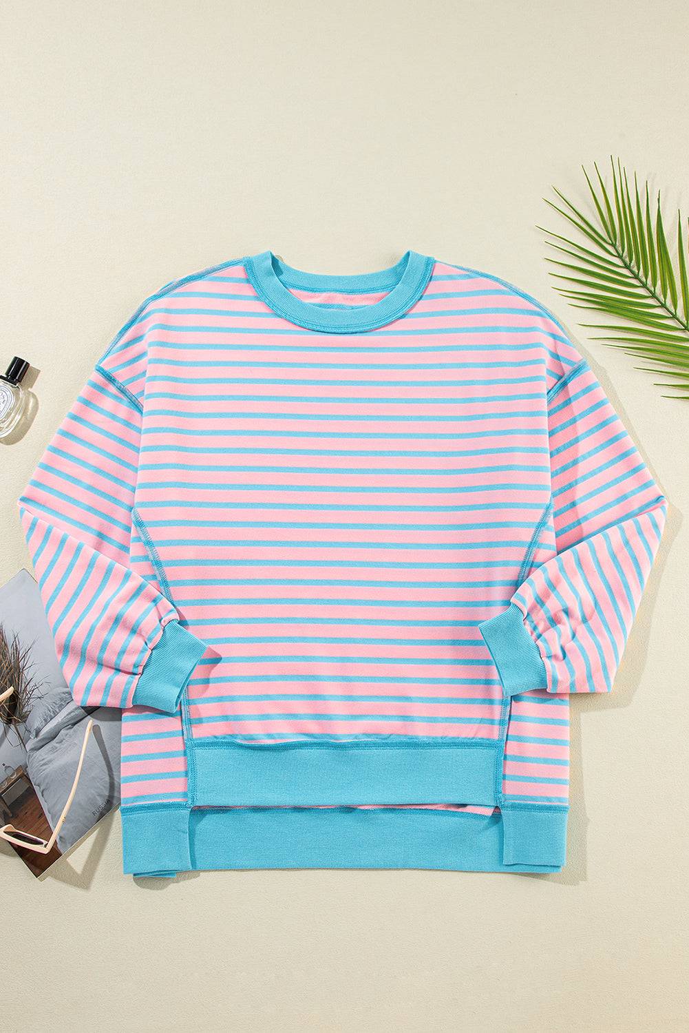 a pink and blue striped sweater next to a pair of sunglasses