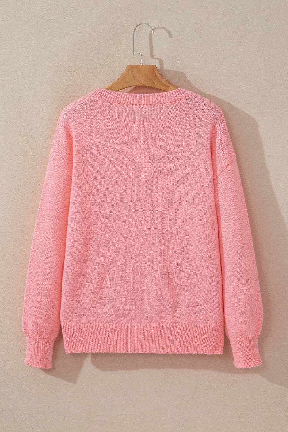 a pink sweater hanging on a wooden hanger