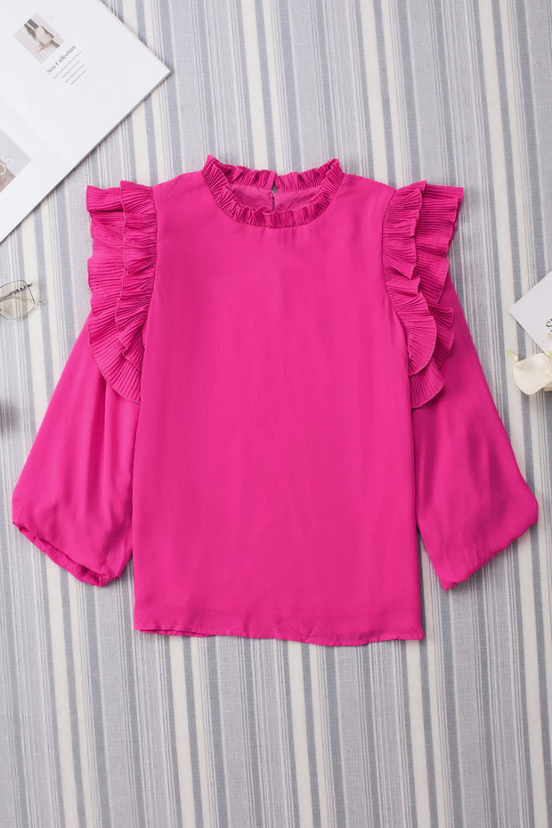 a pink top with ruffled sleeves on a striped wall