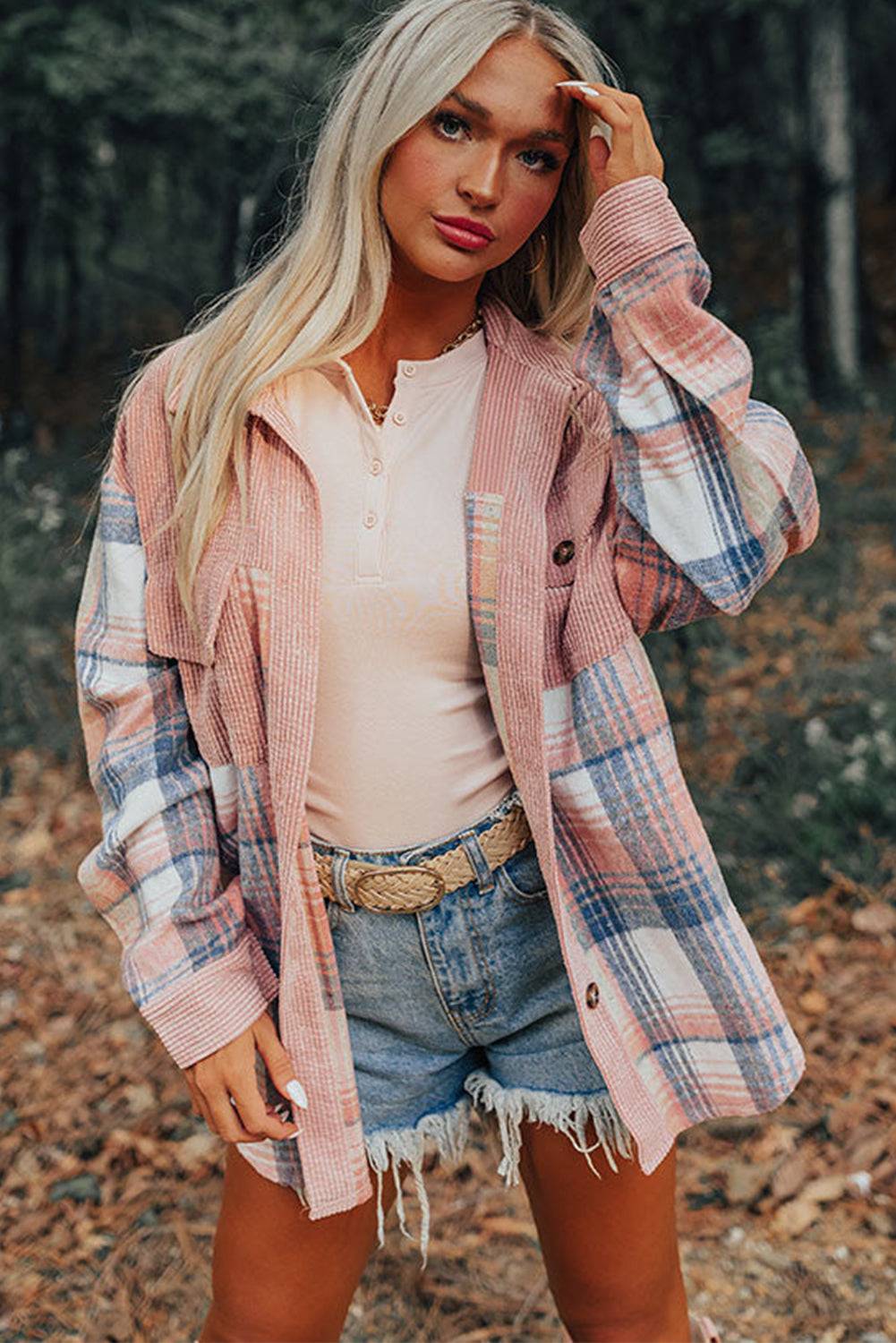 a woman standing in the woods wearing a plaid jacket