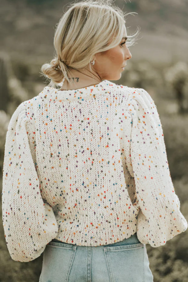 a woman standing in a field wearing a sweater