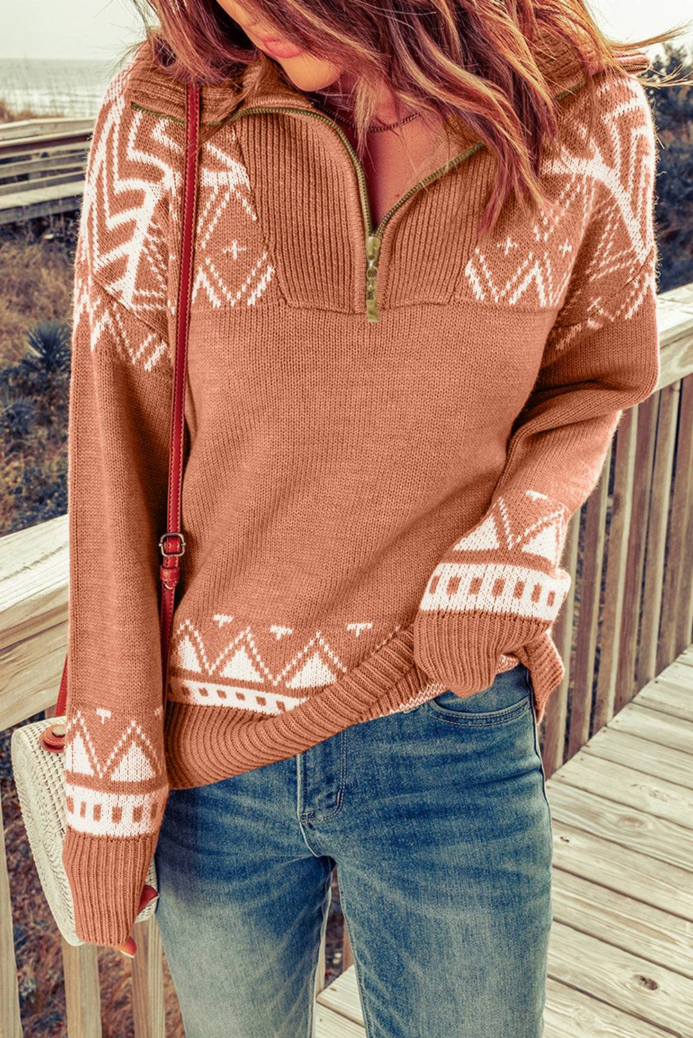 a woman standing on a deck wearing a sweater and jeans