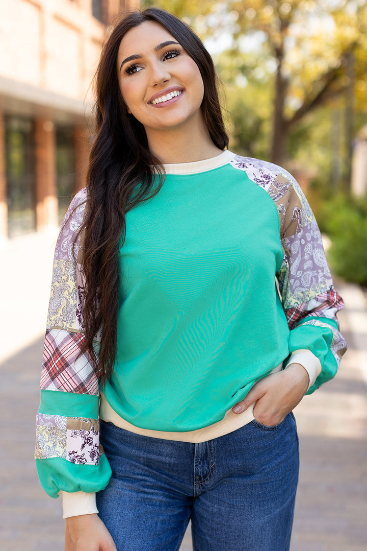 Smiling model wearing Aruba Blue Plaid Vintage Paisley Patchwork Long Sleeve Raglan Top, perfect for fall. Shop at Faith & Co. Boutique.