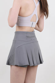 a woman wearing a gray skirt and a sports bra